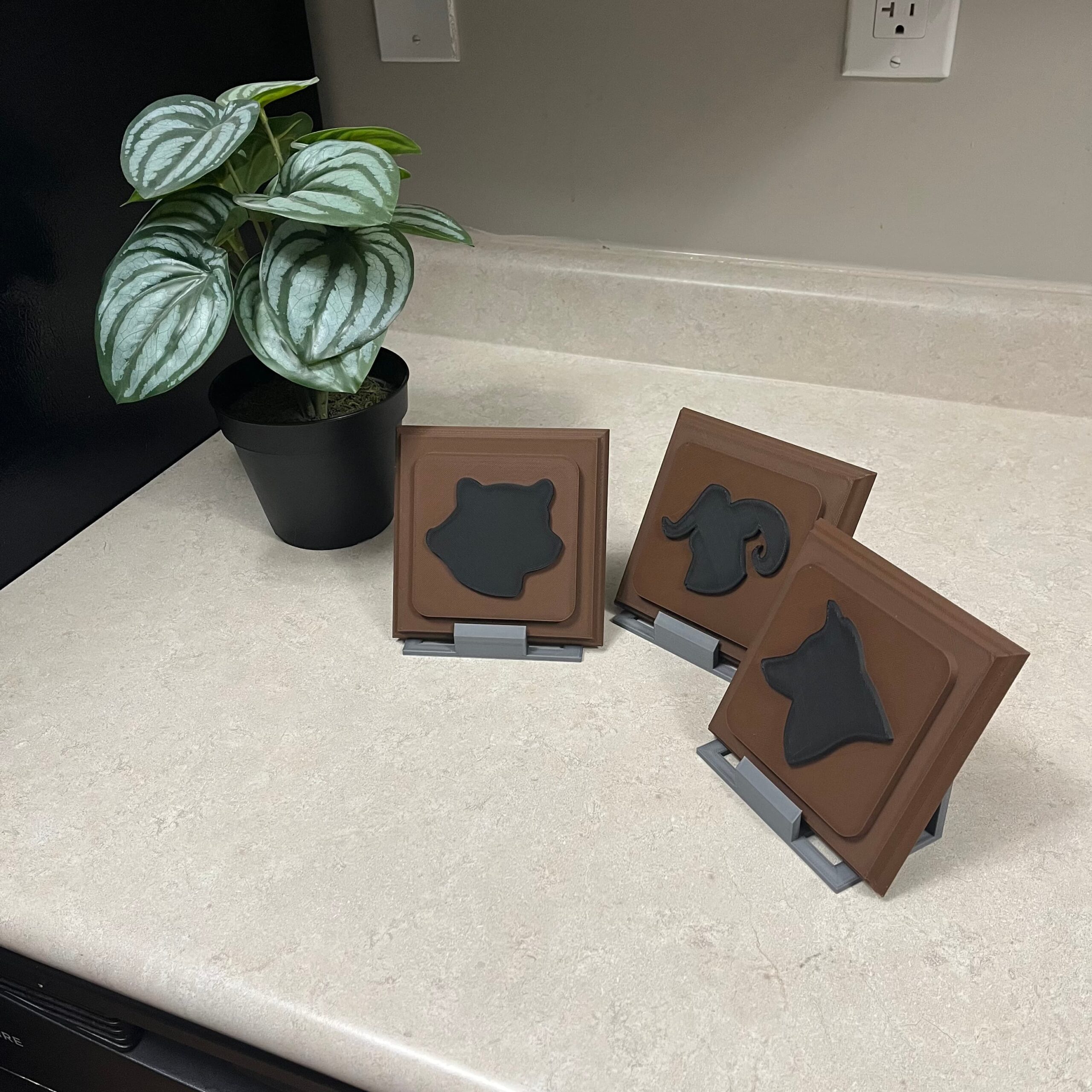 A set of three 4 inch square plaques with animals heads on them.